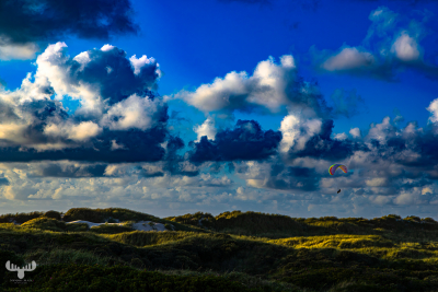 13916 - Paraglider above dune landscape with dramatic sky