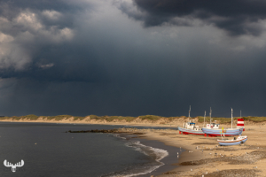 Fishing boats at Vorupør beach under thunderstorm sky
