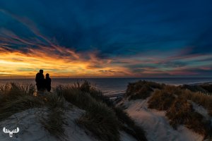 13945 - Two persons silhouette against colorful sunset over North Sea
